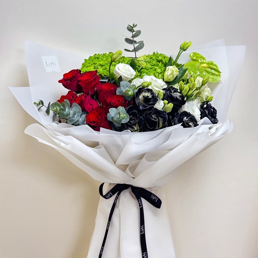 تنسيق الأناقة الإماراتية الصغير مع ورود حمراء عميقة، هيدرنجيا خضراء، وورود مرشوشة باللون الأسود