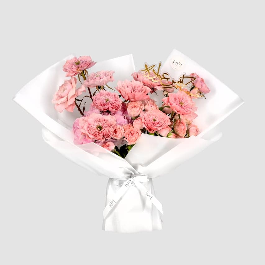  تألق العيد – باقة زهور ناعمة باللون الوردي تضم كوبية وورود.