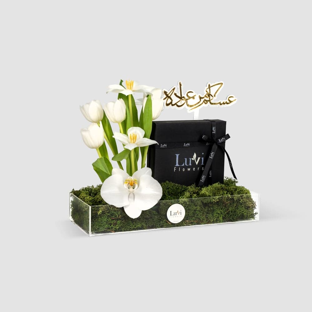  أناقة العيد – تنسيق زهور التوليب البيضاء والأوركيد في صندوق أكريليك مع شوكولاتة. thumbnail