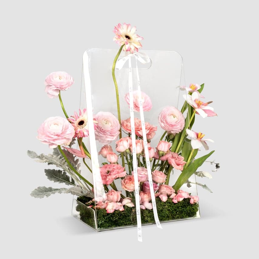 Luvi Luxe – Pink Ranunculus, Gerbera, and white Tulips in an acrylic bag.