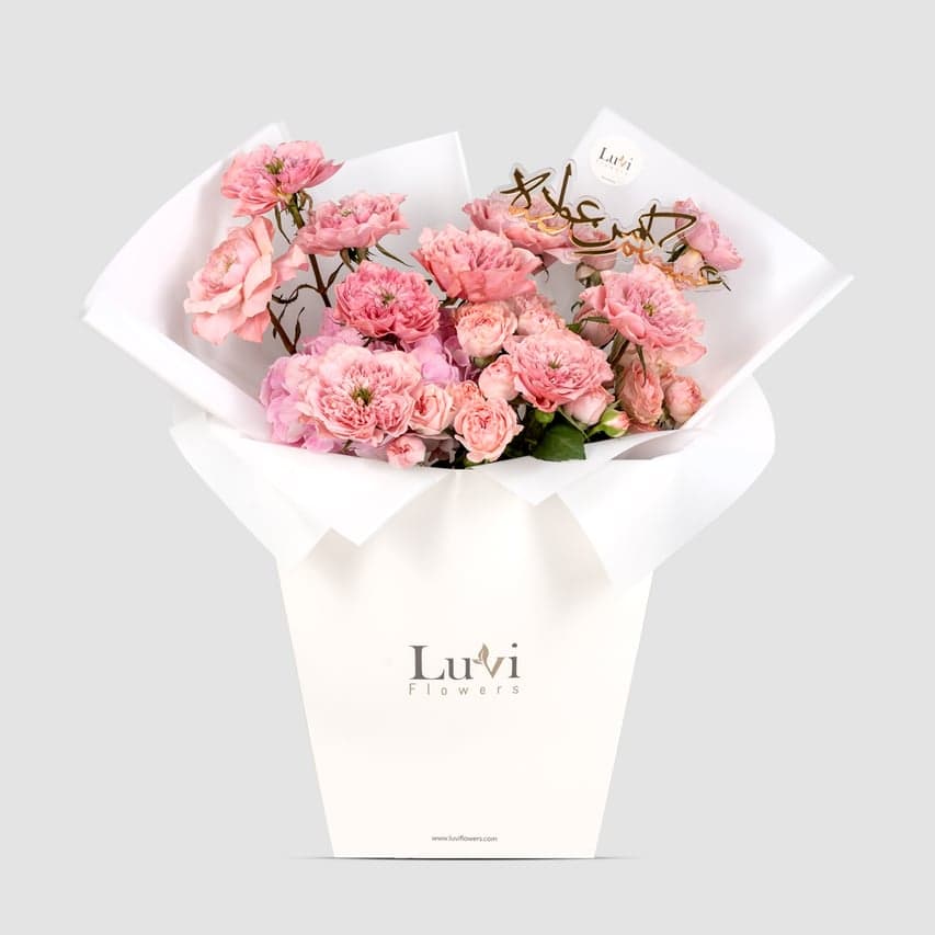  تألق العيد – باقة زهور ناعمة باللون الوردي تضم كوبية وورود.