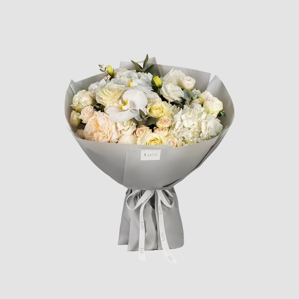 باقة أناقة الزفاف تضم زهور الهيدرنجيا البيضاء، أقحوان البينغ بونغ، الورود، أوركيد الفالاينوبسيس، الليسيانثس الأبيض، الكافور، وورود الرش البيج